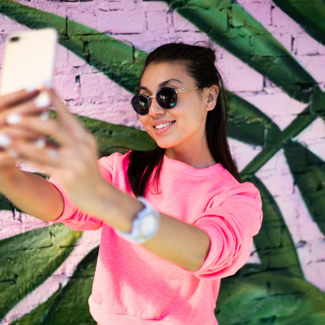 Woman taking selfie in pink shirt with botanical background